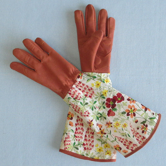 Pair of brown gardening gloves with floral cuffs on a light blue background