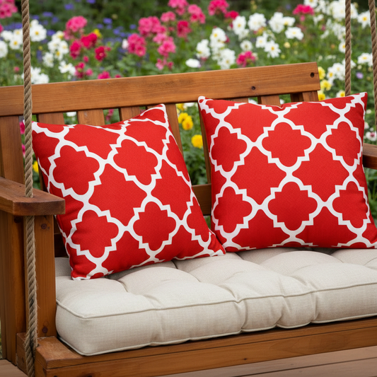 Red and white patterned pillows on a wooden swing with a blue cushion.