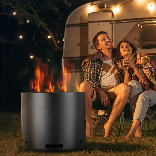 Two people sitting by a fire pit in front of a camper van at night.